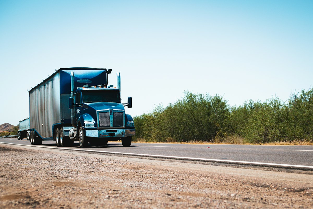 Blue semi-truck pulling a trailer on an open highway